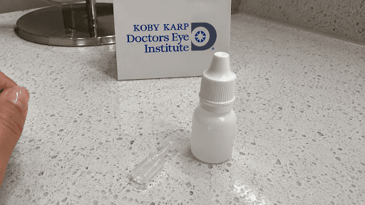 Preservative-free single-use eye drop vial next to a standard multi-dose bottle on a bathroom countertop, illustrating the choice of best dry eye drops without preservatives.